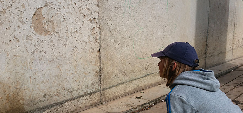 Enfant observant mur avec calcaire à gryphées